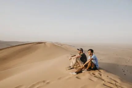 Zwei Männer sitzen auf einer Düne in der Namib Desert in Namibia.