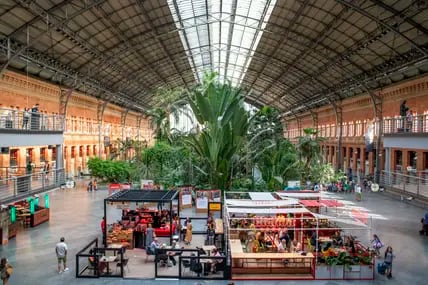 Pflanzen in der Haupthalle neben Bars und Restaurants im Bahnhof Atocha in Madrid.