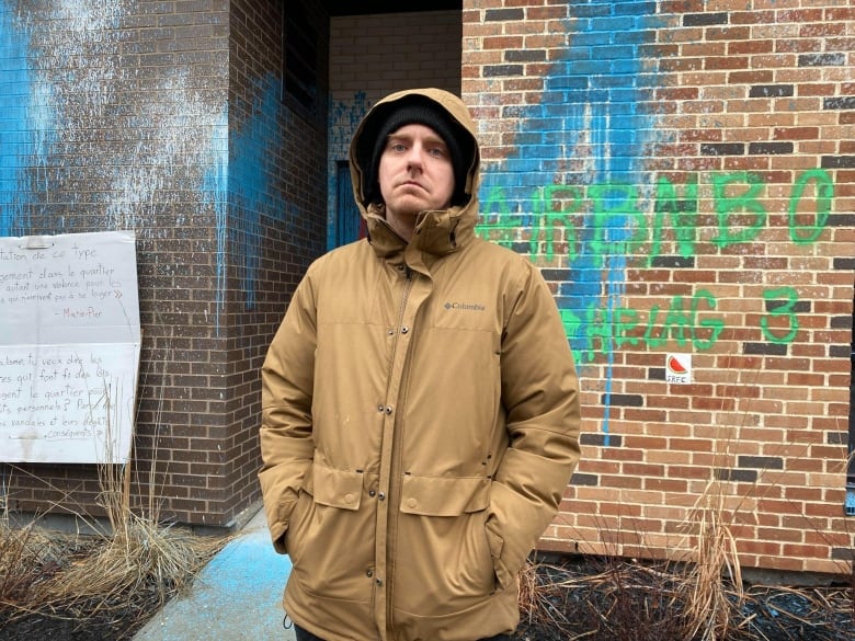 A man stands in front of a building.