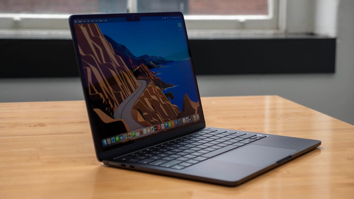 Apple MacBook Air M3 13-inch laptop on a wood table with windows in the background.