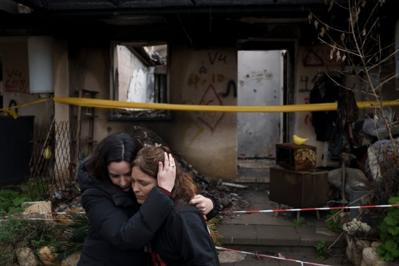 Amit Soussana, 40, right, is embraced by a friend after speaking to journalists in front of her destroyed house in the kibbutz Kfar Azza, near the Gaza Strip, Israel, Monday, Jan. 29, 2024. 