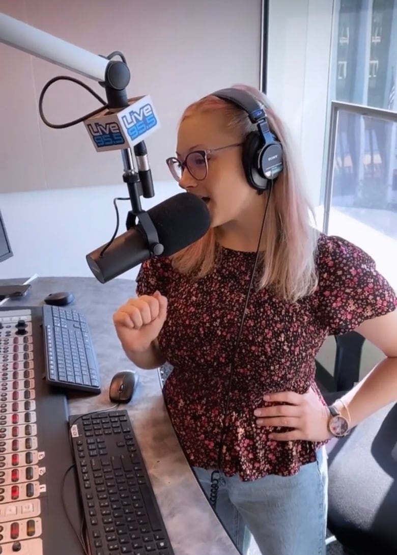 Photo of a caucasian woman in a broadcast studio speaking into a radio microphone.