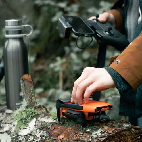 Autel Nano Plus drone on fallen tree being adjusted by user.