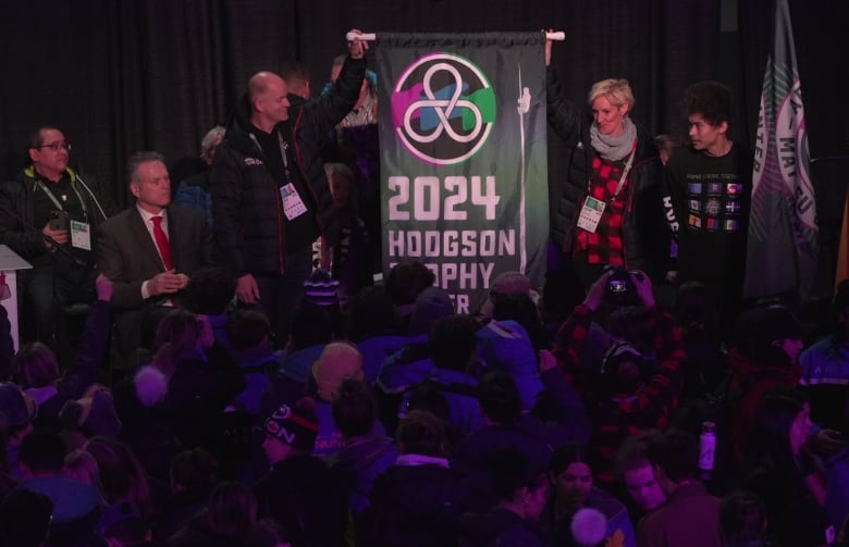 Two adults hold up a flag that says Hodgson Trophy winner