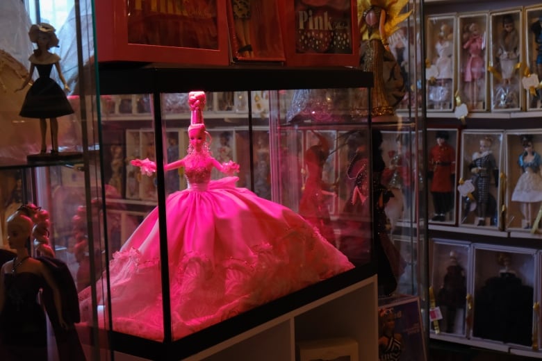 A barbie is in a glass case