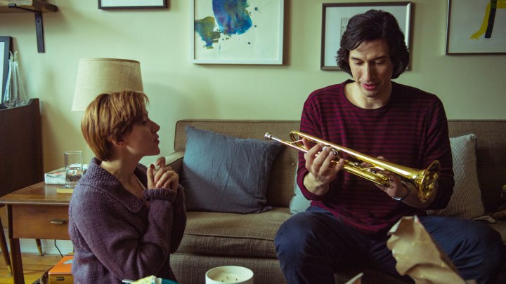 Adam Driver holds a trumpet next to Scarlett Johanson.