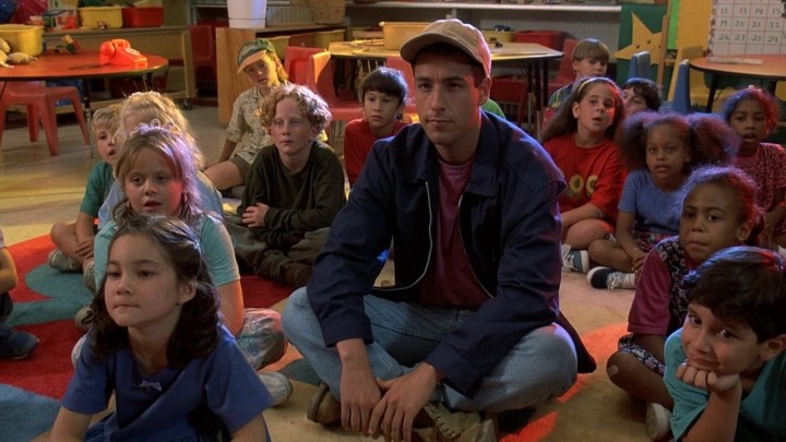 Adam Sandler sitting on the floor with a bunch of kindergarten kids in a scene from Billy Madison.