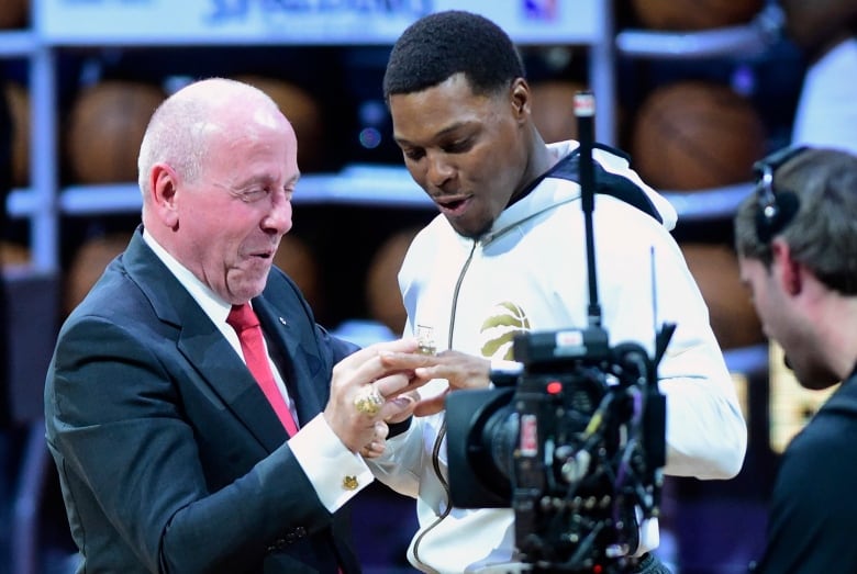 A man presents a ring to a player during a ceremony.