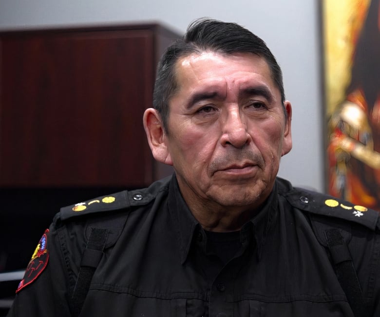 A close-up shot of a man dressed in a black police uniform.