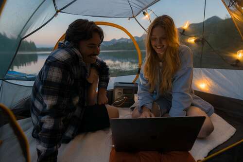 people looking at laptop with Bluetti ac70 behind