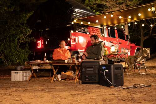 bluetti multicooler and portable power station in foreground with woman and man sat at table outdoors