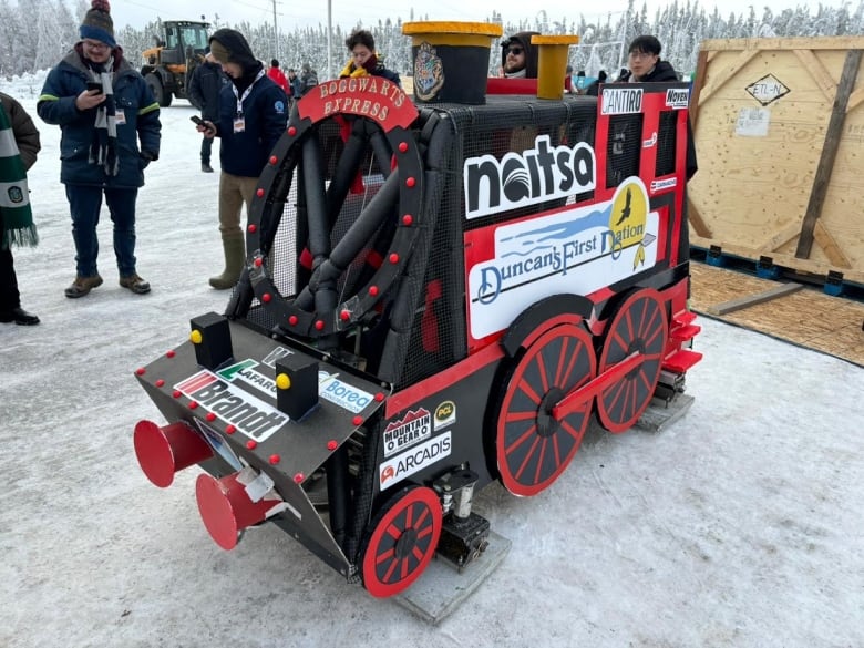 A covered contraption for sliding on snow, painted in red and black to look like a train engine.