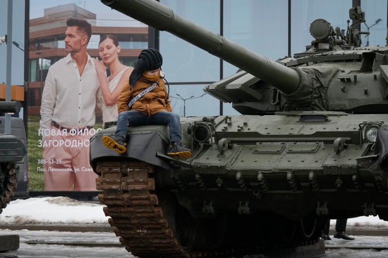 A boy sits on a Russian tank at a weapons exhibition in St. Petersburg, Russia, in February 2024.