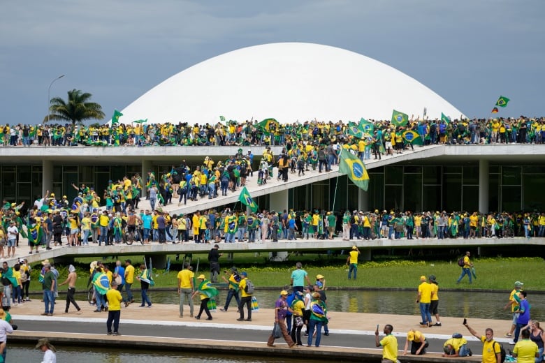 A large crowd of protesters are seen outside a building.