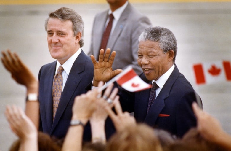 Nelson Mandela greets people as he walks with Prime Minister Brian Mulroney on his arrival in Ottawa, ON June 17, 1990 for a three-day visit to Canada.