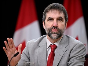 Steven Guilbeault speaks during a news conference with Canadian flags behind him