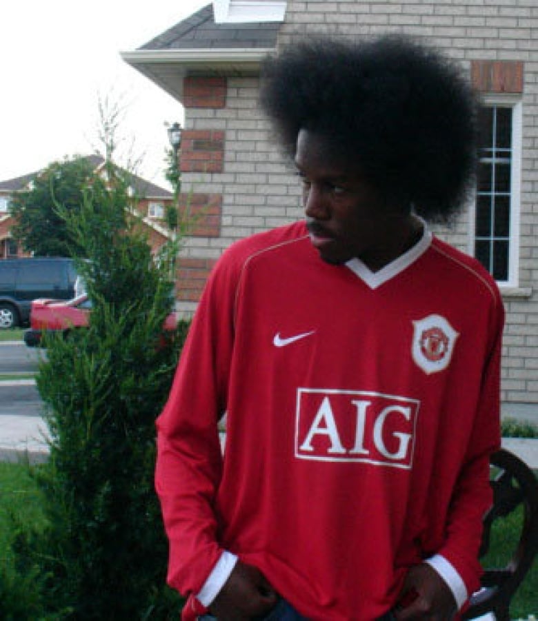 Chris Strikes stands outside Strikes has an Afro hairstyle.