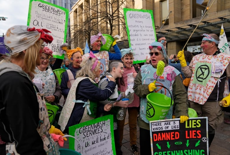 People in costumes and holding placards take part in a demonstration on a city street.