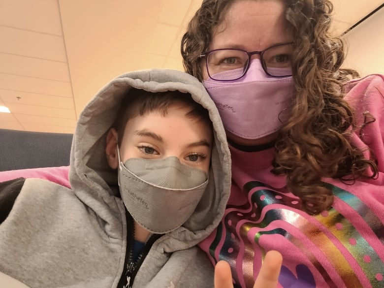 A 12-year-old boy and his mother are pictured, both wearing masks.