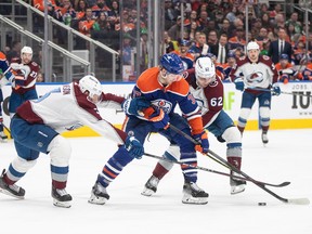 Warren Foegele handles the puck chased by two Avalanche players