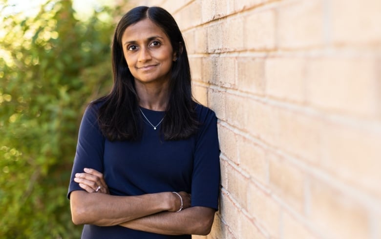 Photo of Dr. Mekalai Kumanan outdoors, leaning against a brick wall