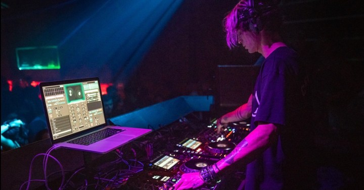 A DJ standing at a mixing board.