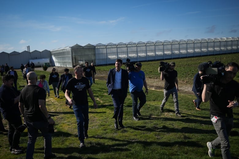 A group of people walking among greenhouses.