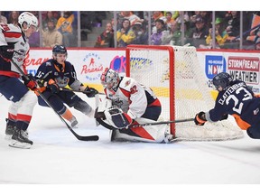 Flint Firebirds' forward Connor Clattenburg, right, tries to bat the puck past Windsor Spitfires' goaltender Max Donoso during Saturday's game at the Dort Financial Center. Windsor defenceman Conor Walton (28) tries to move in to assist while Flint's Jeremy Martin (15) looks for a rebound.