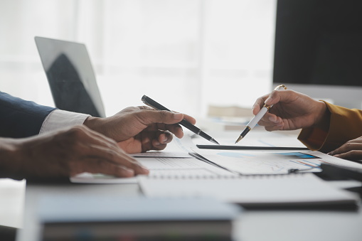 Financial analysts analyze business financial reports on a digital tablet planning investment project during a discussion at a meeting of corporate showing the results of their successful teamwork.