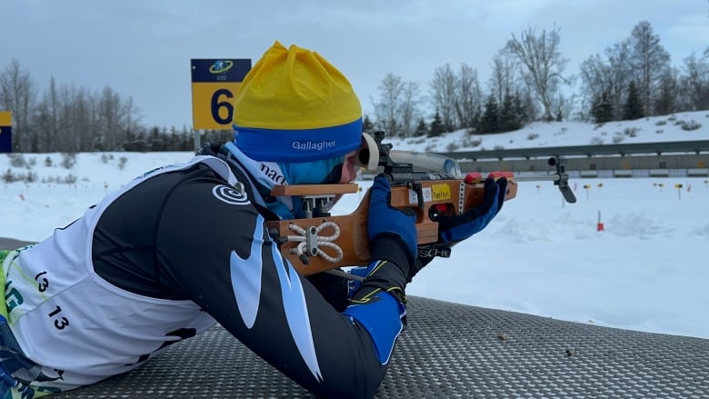 A young man points a rifle at a target.