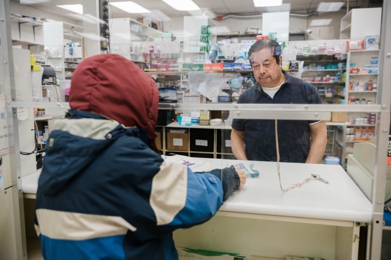 Gary Siu of Garlane Pharmacy in East Vancouver helping a customer at checkout.