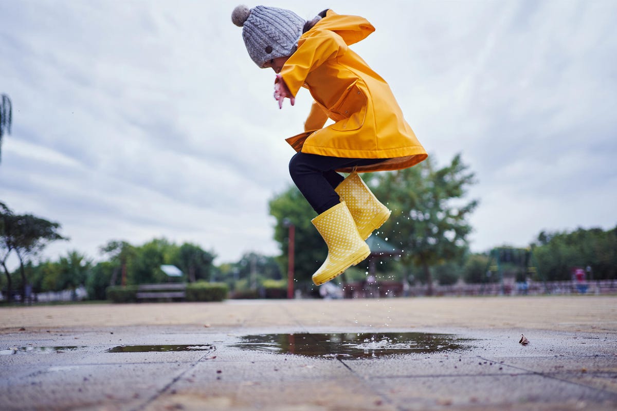 A little kid stomping in a puddle in rain boots