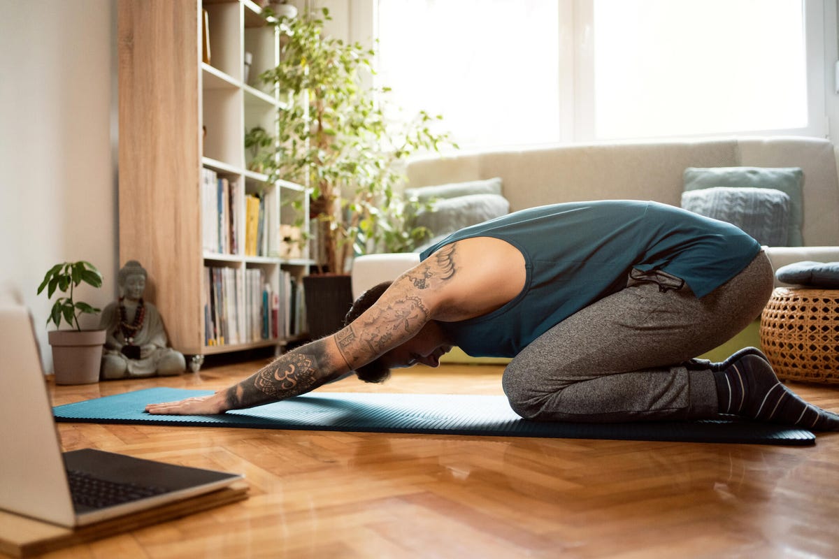 A person in child's pose on their living room floor