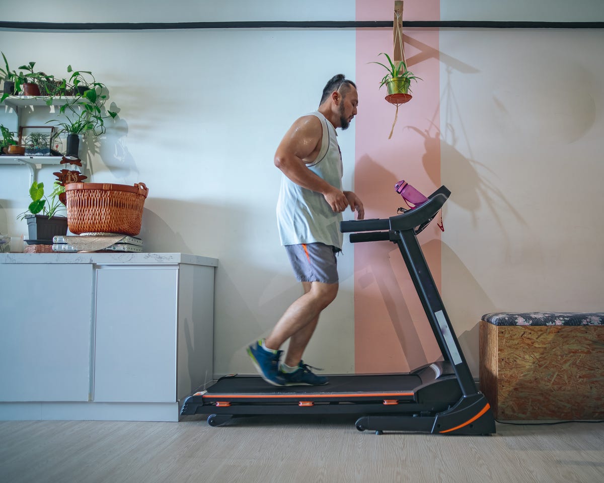 Profile shot of man running on a treadmill at home