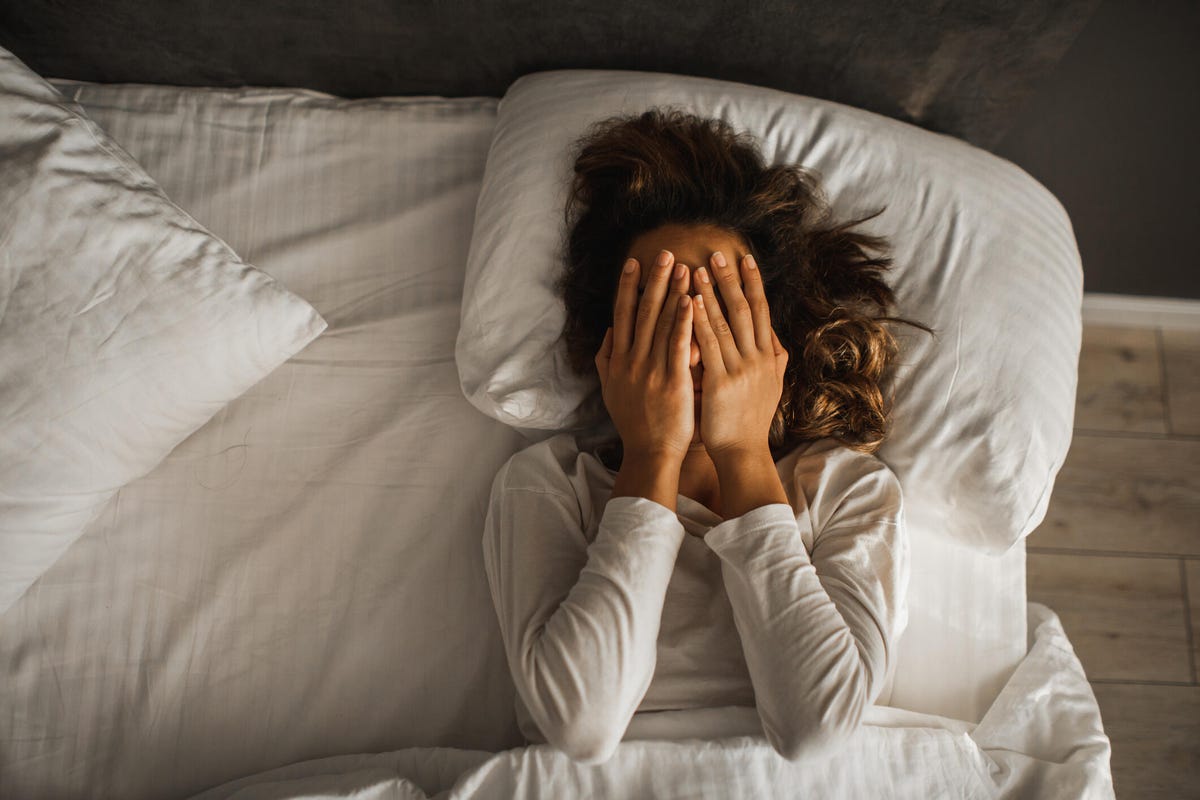 Woman in bed closed face with hands and crying.