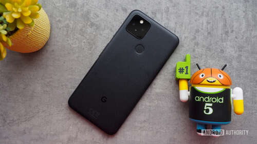 Google Pixel 5 seen from the back, laying on a table with a mini Android basketball figurine next to it