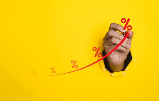 Hand pass thru yellow punched paper with red increasing graph and percentage for financial banking increase interest rate or mortgage investment dividend from business growth concept.