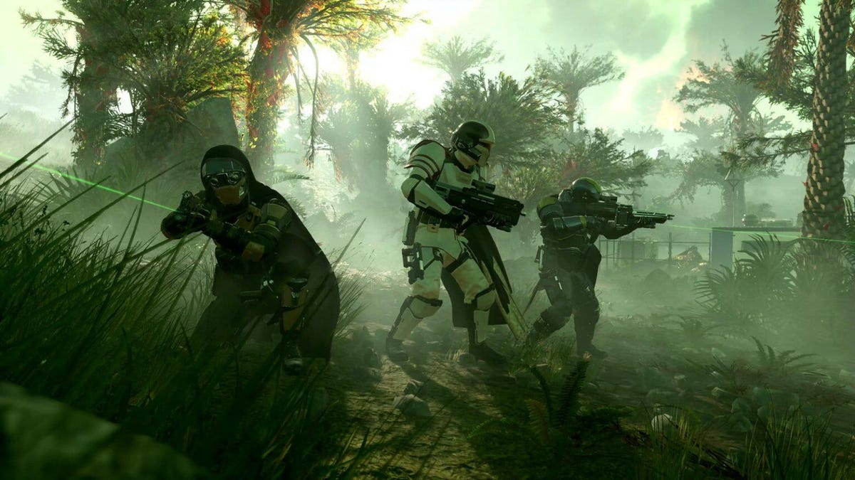 A three-person squad of Helldivers marches through the jungle with various weapons.