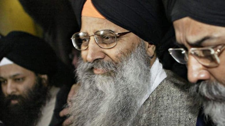 An Indian man wearing a turban and with a grey beard smiles