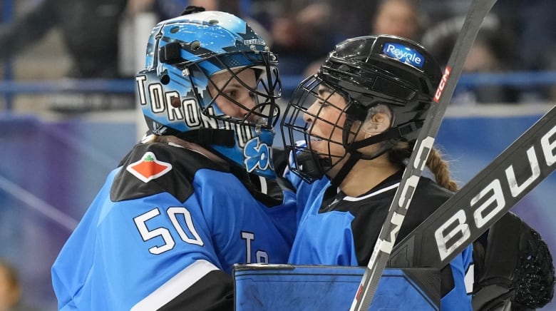 Two women's hockey players celebrate after winning a game. 