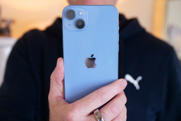 The iPhone 14 Plus held in a man's hand.