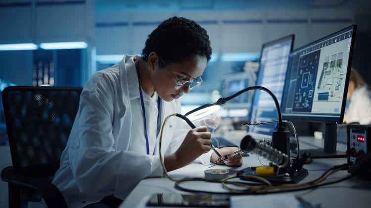 Modern Electronics Research, Development Facility: Black Female Engineer Does Computer Motherboard Soldering. Scientists Design PCB, Silicon Microchips, Semiconductors. Medium Close-up Shot