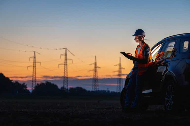 Engineer using digital tablet near car