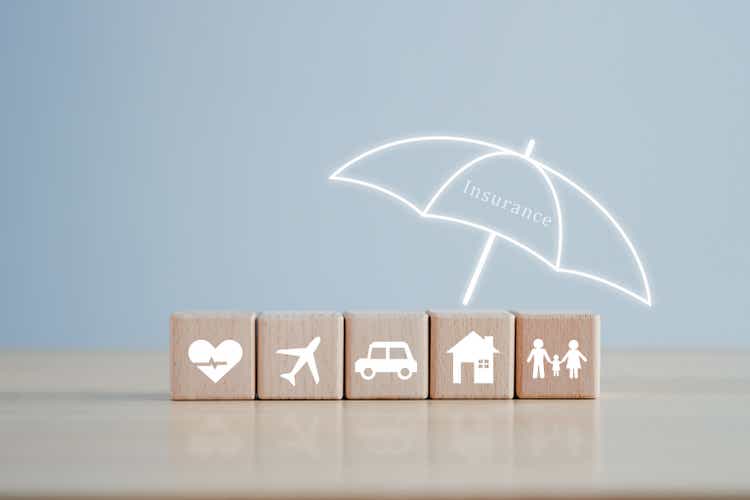 Insurance concept. Protection against a possible eventuality. Umbrella cover House, Car, Family, Travel and Health icon on wooden block for assurance life concept.