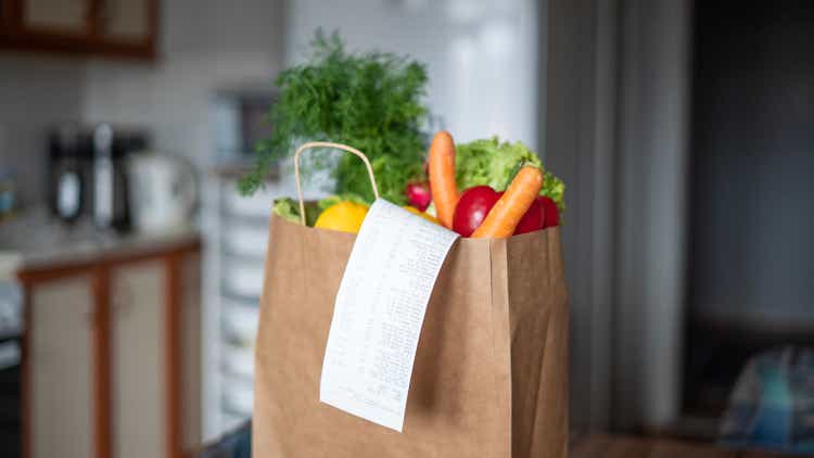 Shopping bag stands on table in kitchen and shopping receipt hangs down from bag