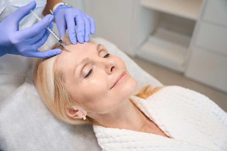 Close up of happy adult lady getting face antiwrinkle injection