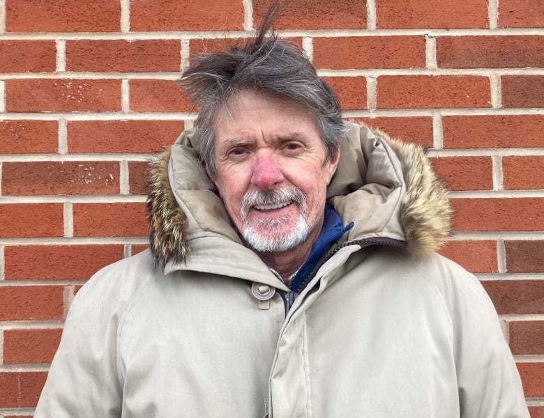 A man standing in front of a brick wall