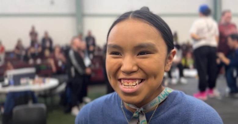 Girl smiles past camera.