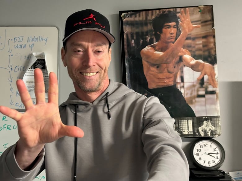 A man stands in front of a poster of Bruce Lee.