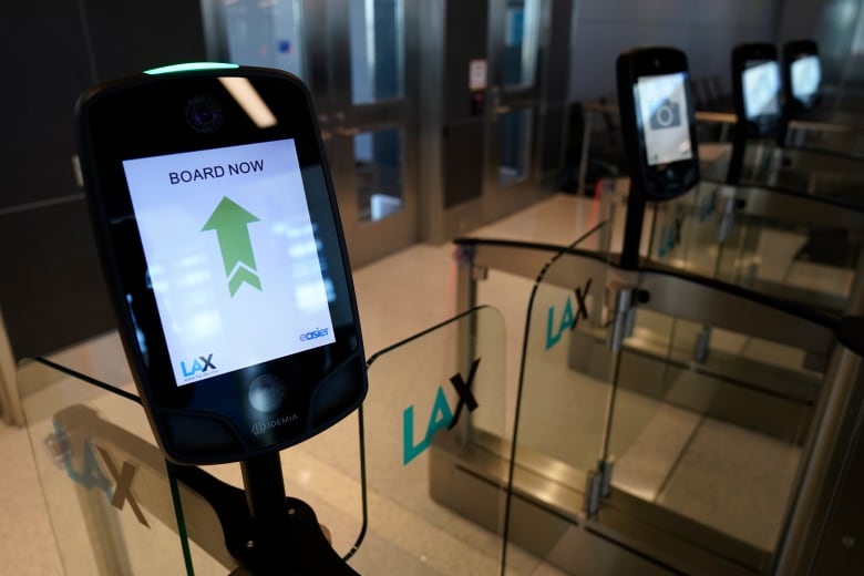 Close up photo of a smart airport gate. A screen displays a green arrow, with the words "Board Now". The clear plastic gates read "LAX"